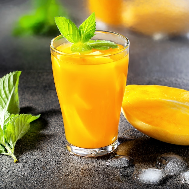 Glass of mango cocktail with mint on bar counter.