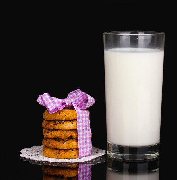 Glass of milk and cookies isolated on black