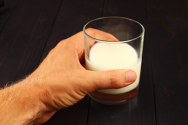 Glass of milk on a dark surface in hand