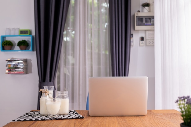 Glass of milk and laptop on living room.