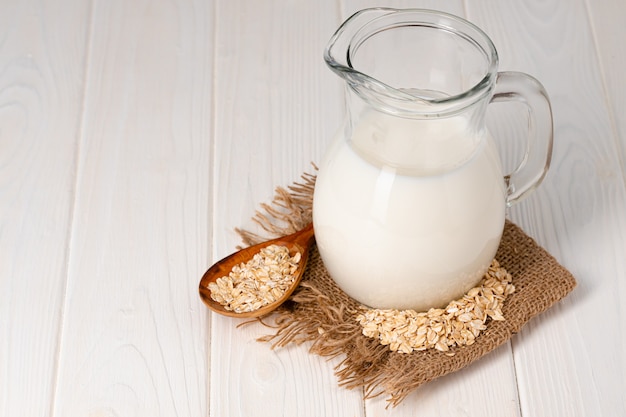 Glass of milk and oat flakes on wooden table