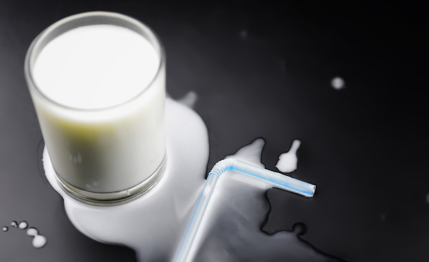 Glass of milk splashing and tube straw on the table