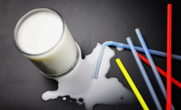 Glass of milk splashing and tube straw on the table