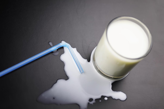 Glass of milk splashing and tube straw on the table