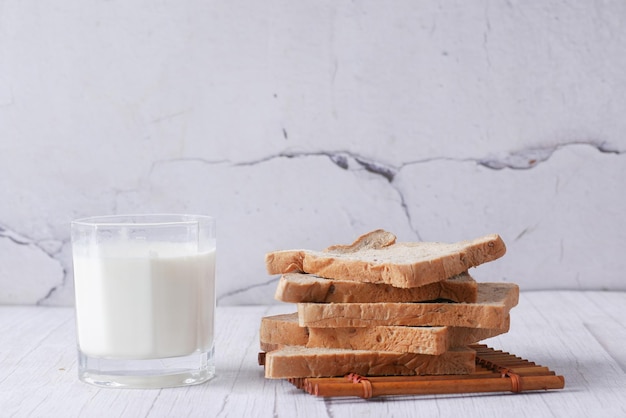 Glass of milk and white bread on table