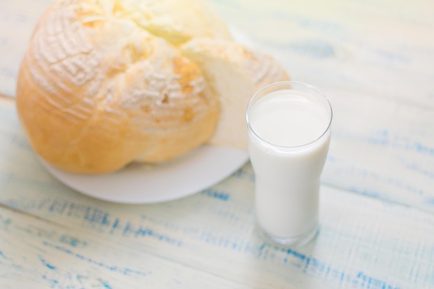 A glass of milk and white bread on a wooden background