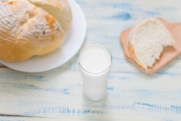 A glass of milk and white bread on a wooden background