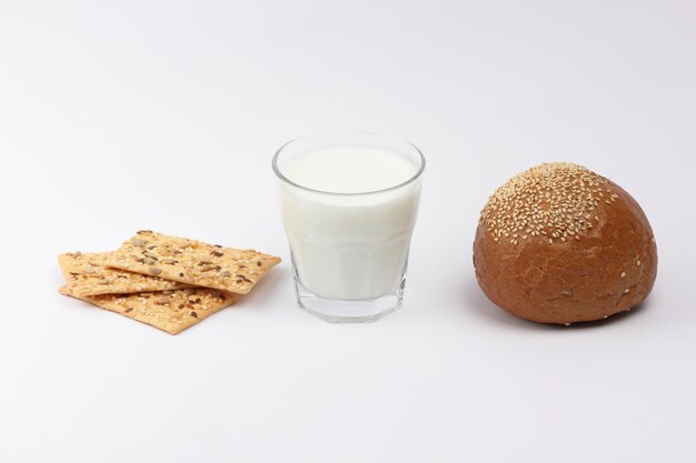 A glass of milk with a rye bun and cereal loaves isolated on a white background Closeup breakfast healthy food