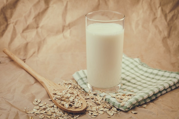 Glass of milk and wooden spoon with oatmeal on crumpled paper background