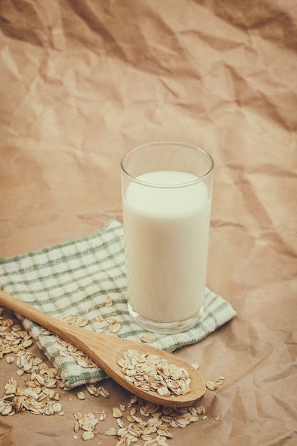 Glass of milk and wooden spoon with oatmeal on crumpled paper background