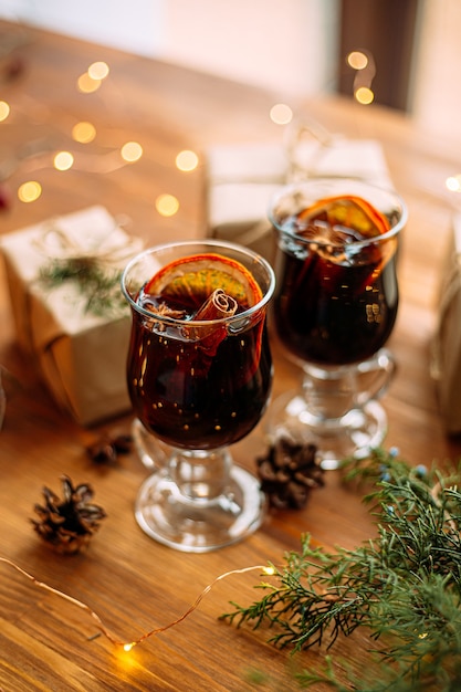 Photo glass mugs of glintwine with and garland lights on the wooden table