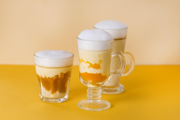 Glass Mugs of Pumpkin Latte Yellow Background Autumn Beverage Horizontal