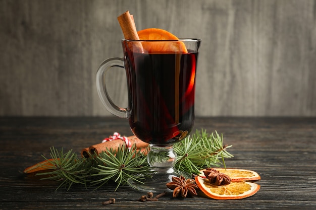 Glass of mulled wine and ingredients on wooden table