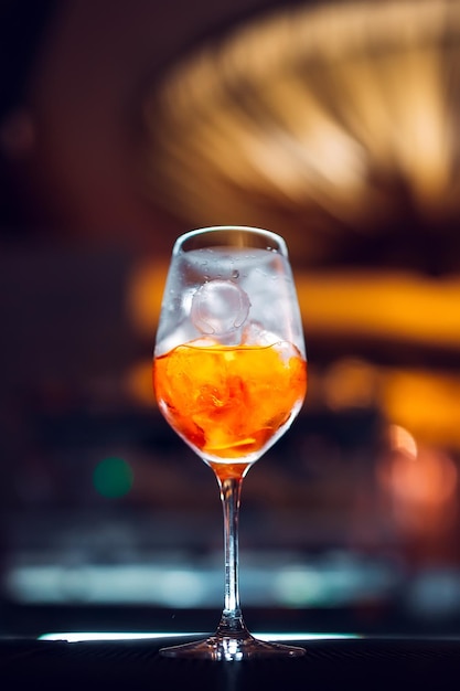 Glass of orange cocktail at bar counter background.