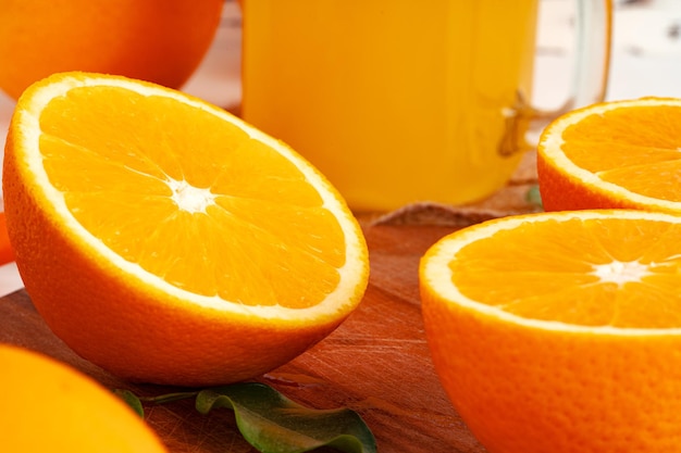 Glass of orange juice and cut oranges on table