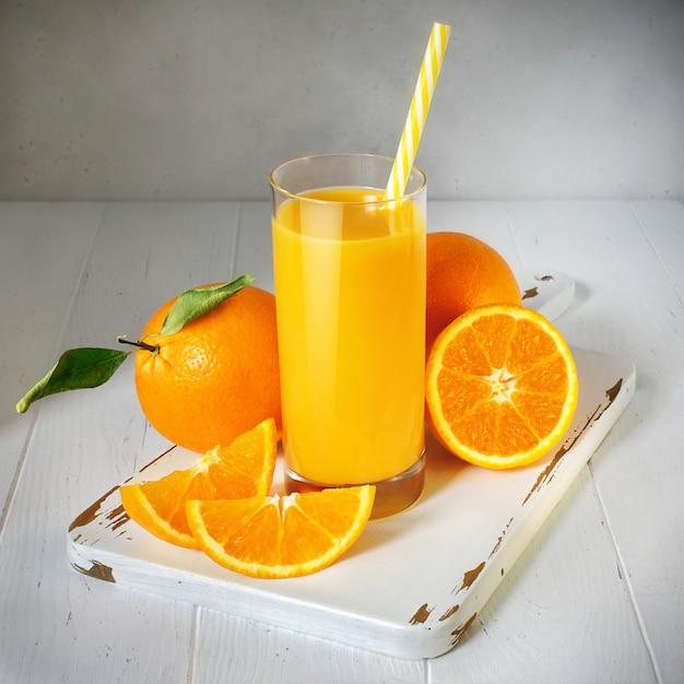 Glass of orange juice and fresh fruit on a white wooden table, vintage style