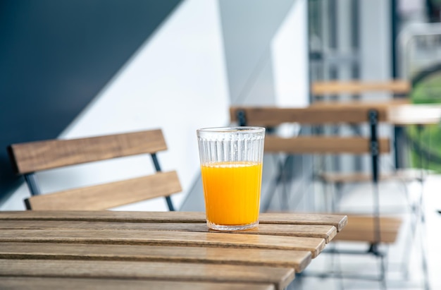 A glass of orange juice on a wooden table on the terrace