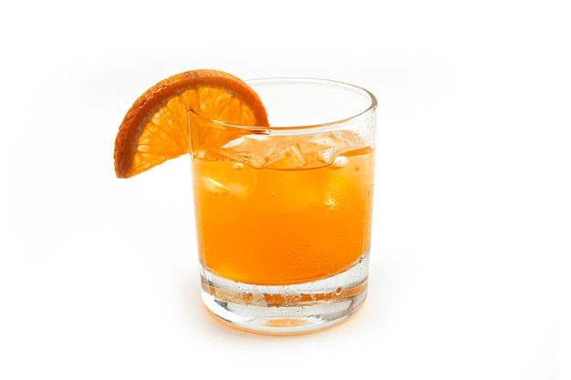 Glass of orange lemonade with slices fruit and ice. Side view.