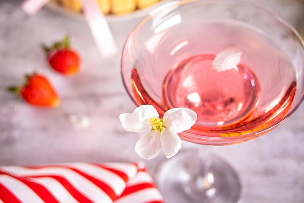 Glass of pink cocktail with flowers branch of apple tree and sweet fresh strawberries Wedding or Valentines day romatic date couple concept Top view