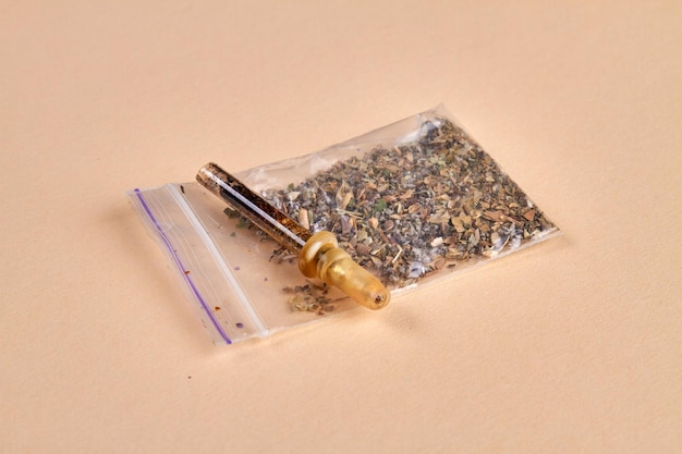 Glass pipette cigarette and pack of weed on beige background drug addicted smokers accesories