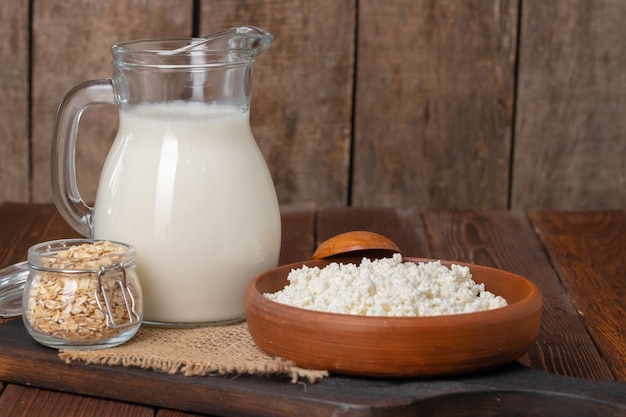 Glass pitcher of milk and bowl of cottage cheese on wooden table