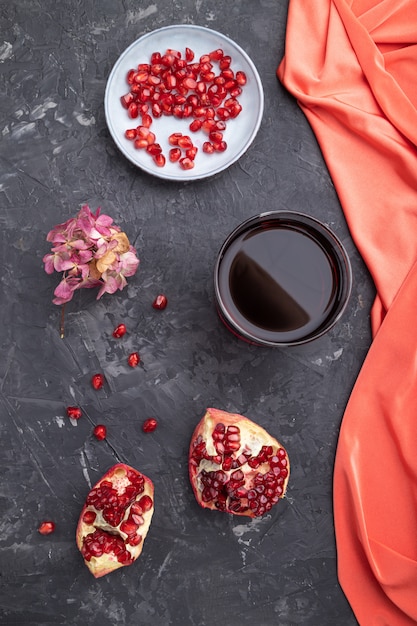 Glass of pomegranate juice on a black concrete background