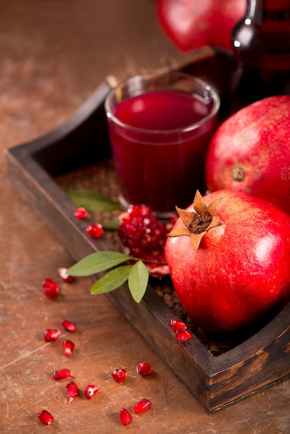 Glass of pomegranate juice and pomegranate fruit on wooden background