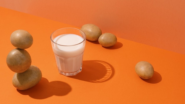 A glass of potato milk on the table with potatoes