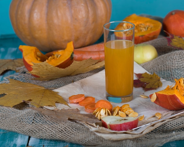 Glass of pumpkin juice on wooden surface. Closeup