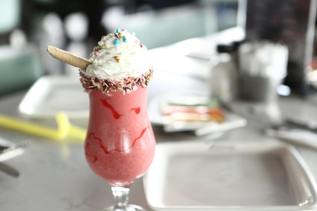 Glass of raspberry milkshake with whipped cream and fresh raspberries