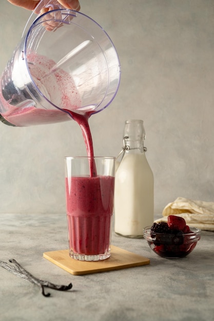 A glass of raspberry smoothie being poured into a glass.