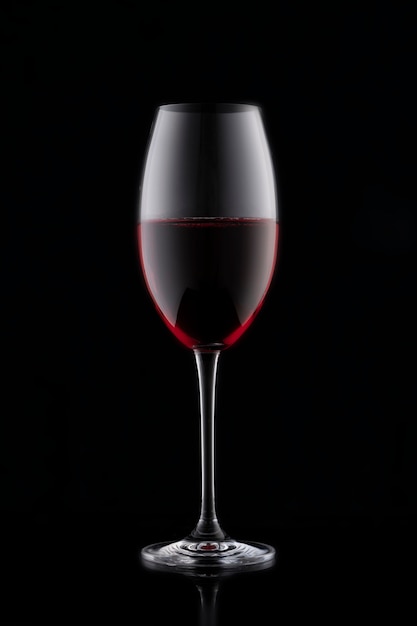 A glass of red wine on a black background.