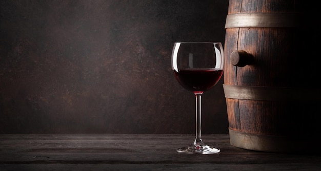 Glass of red wine and old wooden barrel