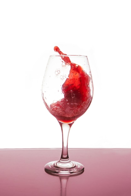 Glass of red wine splashing isolated