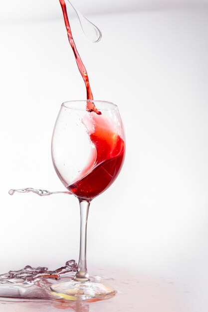 Glass of red wine with splashes on white