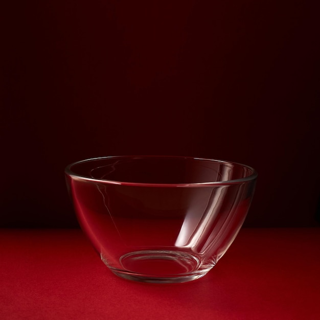 Glass salad bowl on red background