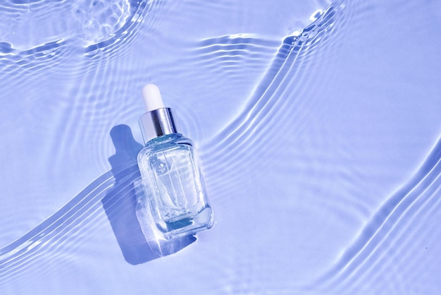 Glass serum bottle with collagen on purple water background