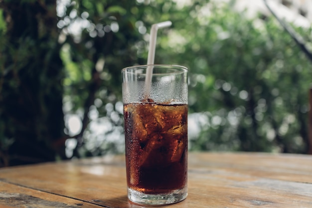 Glass of soda with a white straw on table.