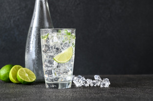 Glass of sparkling water with ice cubes and slice of lime