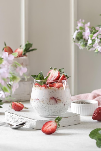 A glass of strawberry chia pudding with strawberries on top.