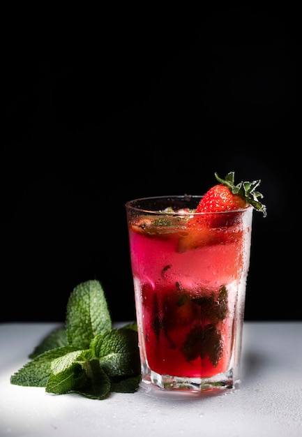 Glass of strawberry drink on a dark background