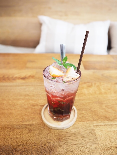 Glass of strawberry juice with soda on wooden table