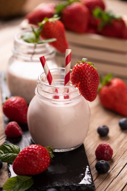 Glass of strawberry smoothie on wooden background cllose up