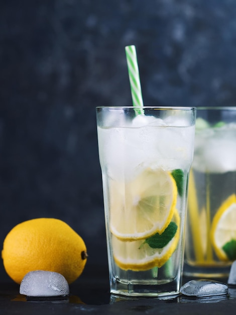 A glass of summer lemonade with lemon mint ice on a dark concrete table