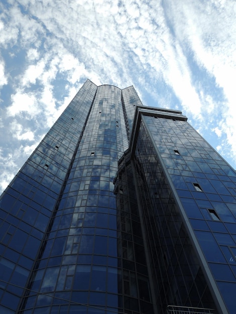 Glass surface of front part of high-rise skyscraper with sky reflection in windows