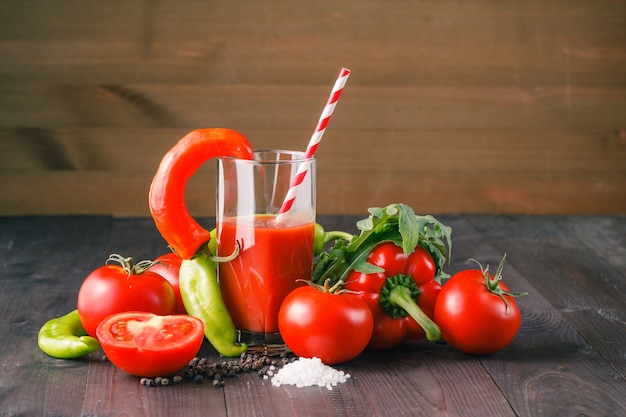 Glass of tasty tomato juice and fresh tomatoes on table