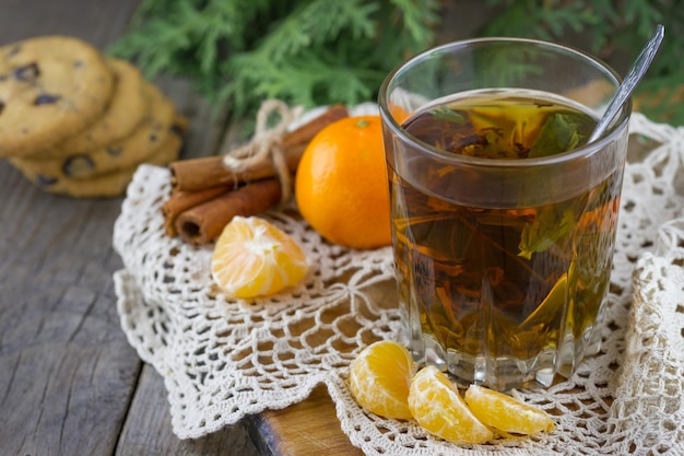 A glass of tea with tangerine and Christmas branches