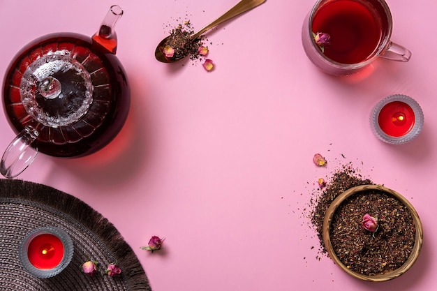 Glass teapot cup of tea and tea leaves on pink background Hot herbal tea is in the glass teapot on the table Copy space