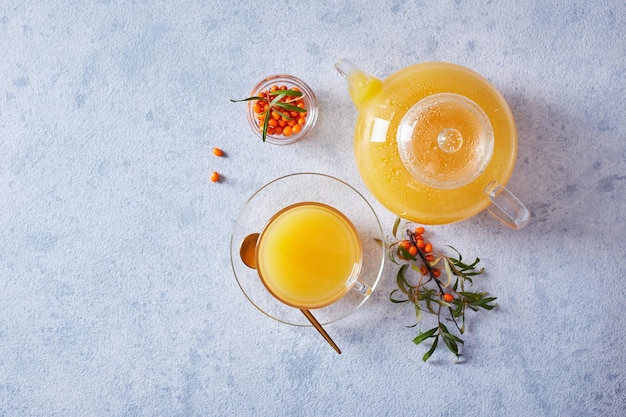 Glass teapot with sea buckthorn tea on a light background