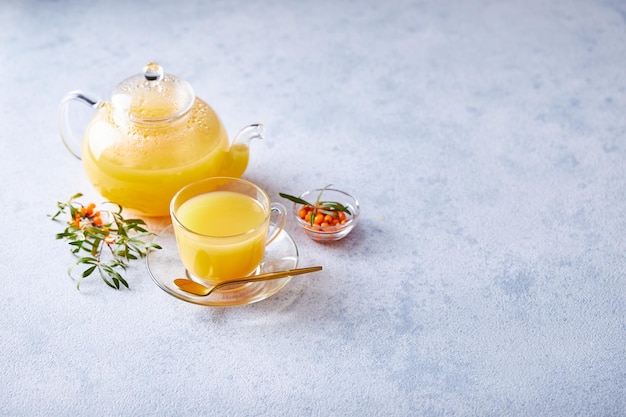 Glass teapot with sea buckthorn tea on a light background